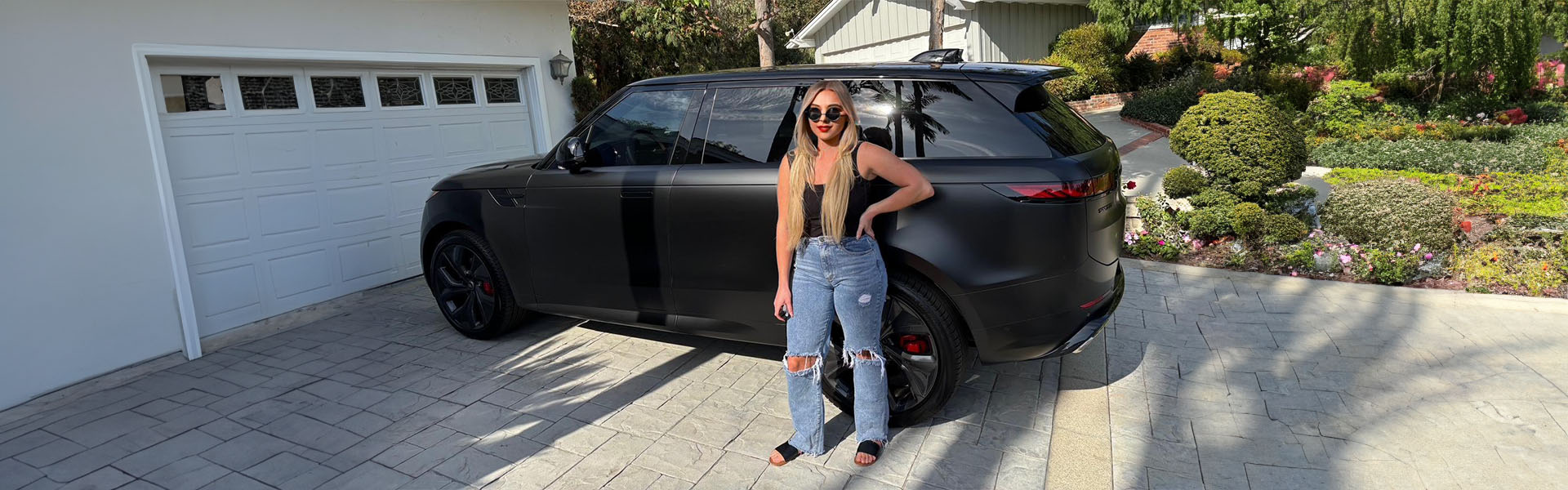 Happy customer in driveway with their new car.