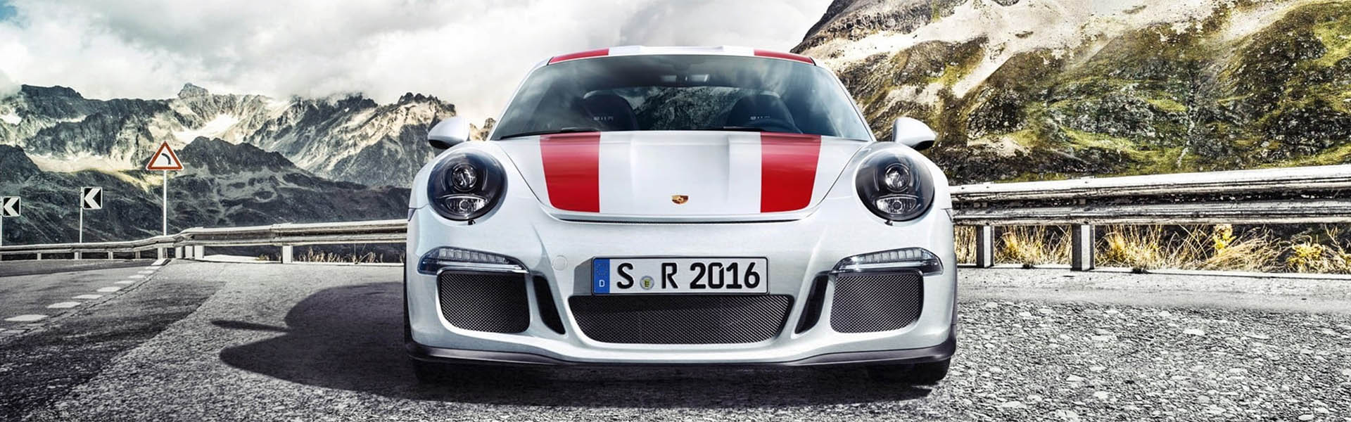 Front view of a white Porsche sports car against a dramatic mountain backdrop, showcasing performance and style at Icon Servicing.