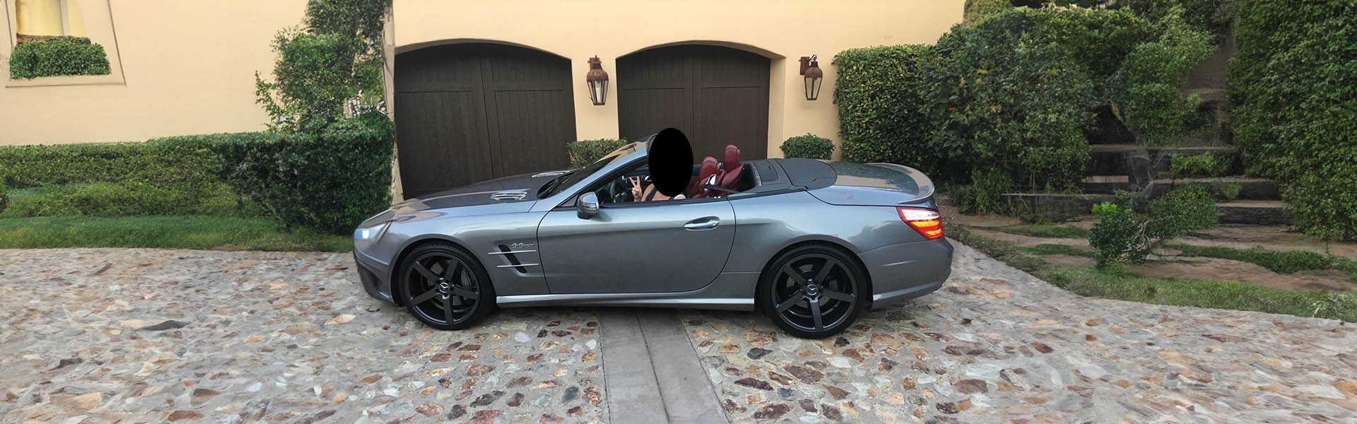 A gray Mercedes-Benz convertible with a happy customer, showcasing customer satisfaction and luxury at Icon Servicing.