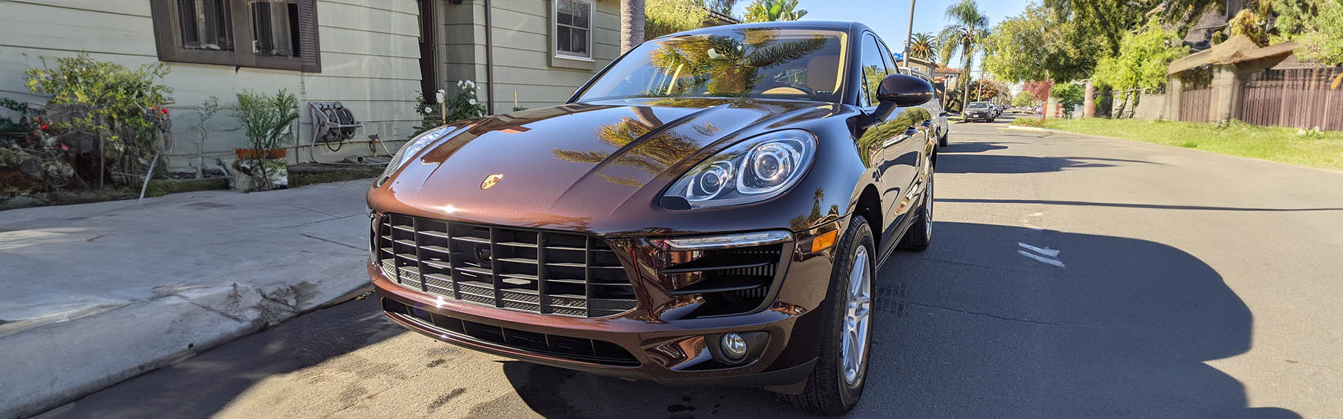 A luxurious brown Porsche SUV parked in a sunny residential area, showcasing the premium and elegant vehicles available at Icon Servicing.