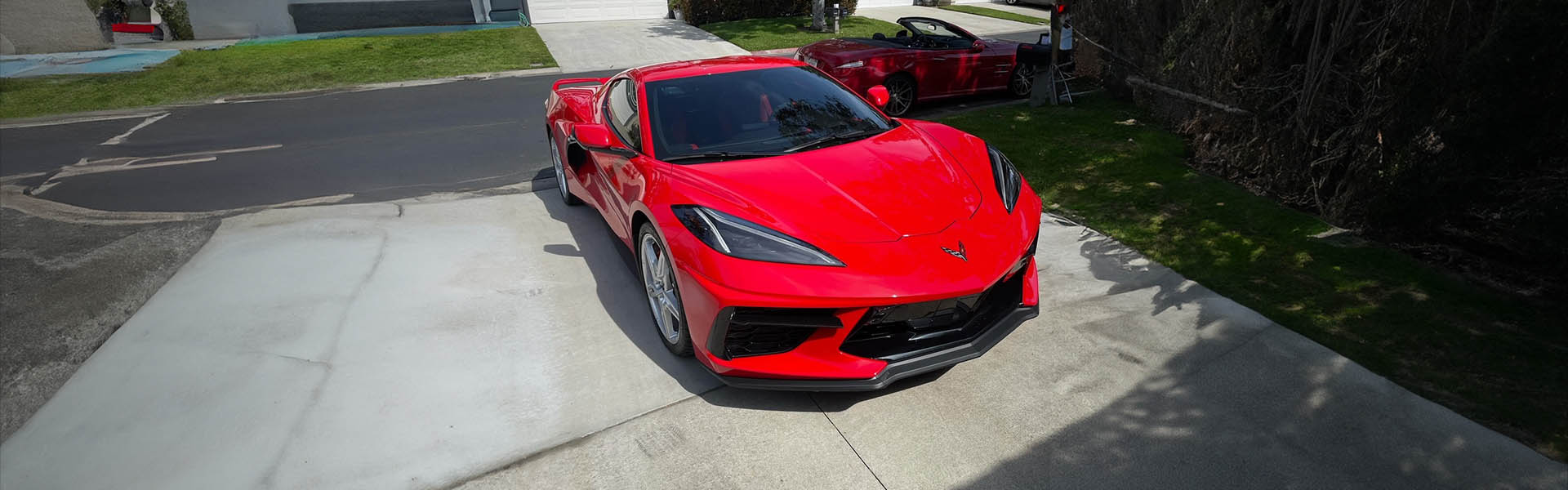 A striking red Corvette in a residential driveway, illustrating the high-end vehicles available at Icon Servicing.