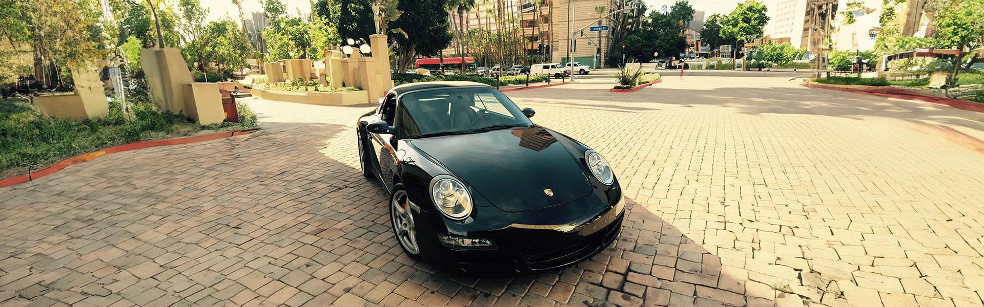 A sleek black Porsche parked in a vibrant urban setting, reflecting the luxury and exclusivity of Icon Servicing's offerings.