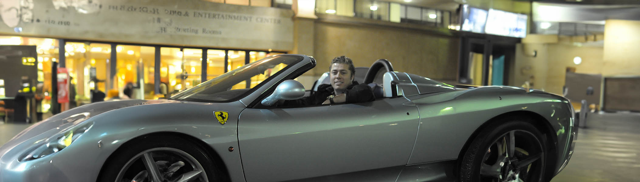 Tom Lawson enjoying a ride in a silver Ferrari, capturing the thrill and excitement of driving luxury cars from Icon Servicing.