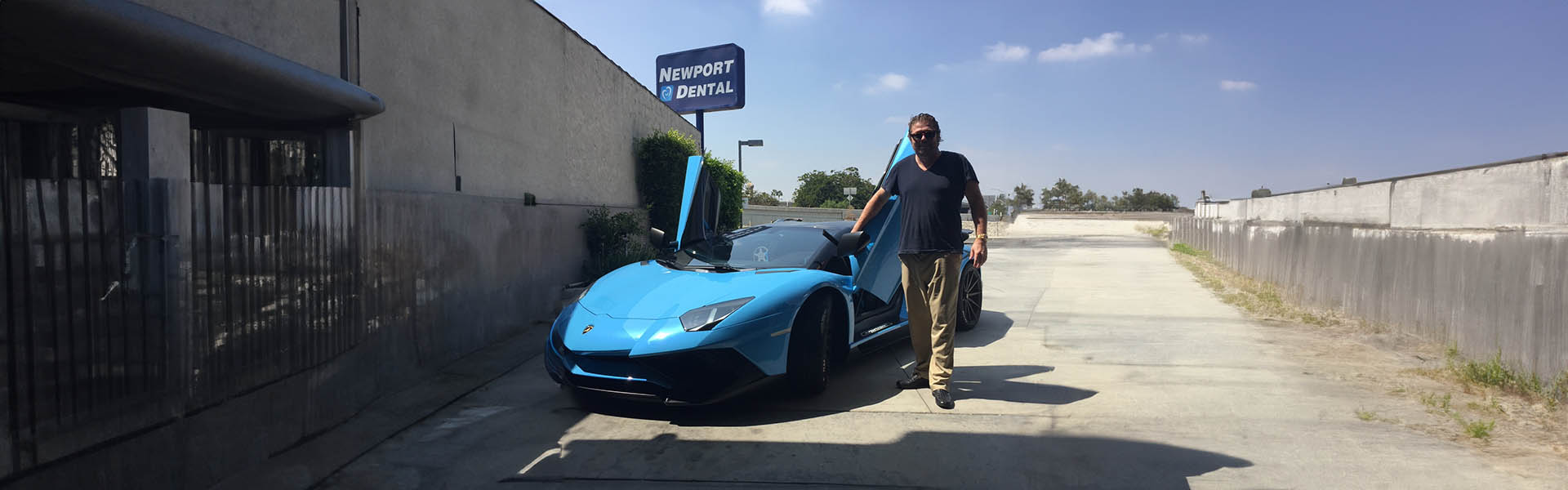 Tom Lawson standing beside a blue Lamborghini with butterfly doors, exemplifying the exotic car sales expertise at Icon Servicing.