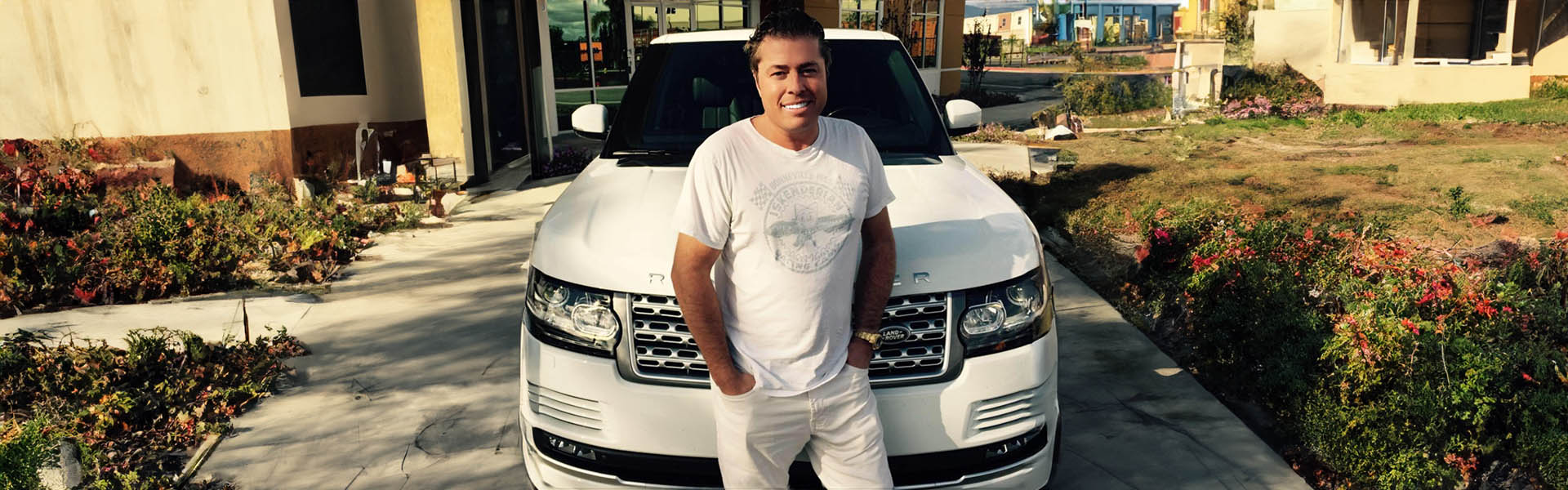 Tom Lawson smiling in front of a white Range Rover, highlighting the personal service and premium vehicles at Icon Servicing.