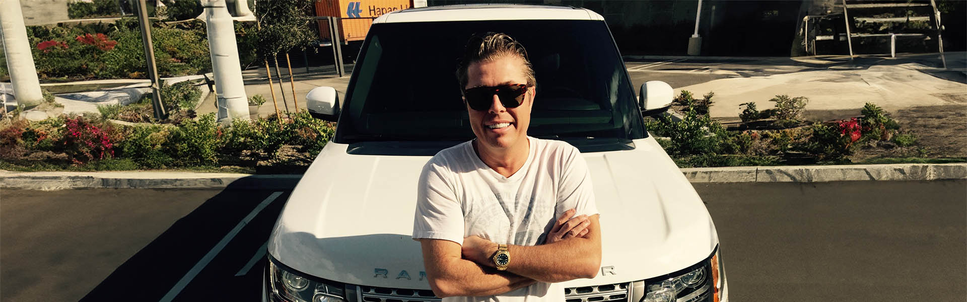 Tom Lawson, owner of Icon Servicing, standing confidently in front of a luxury Range Rover.