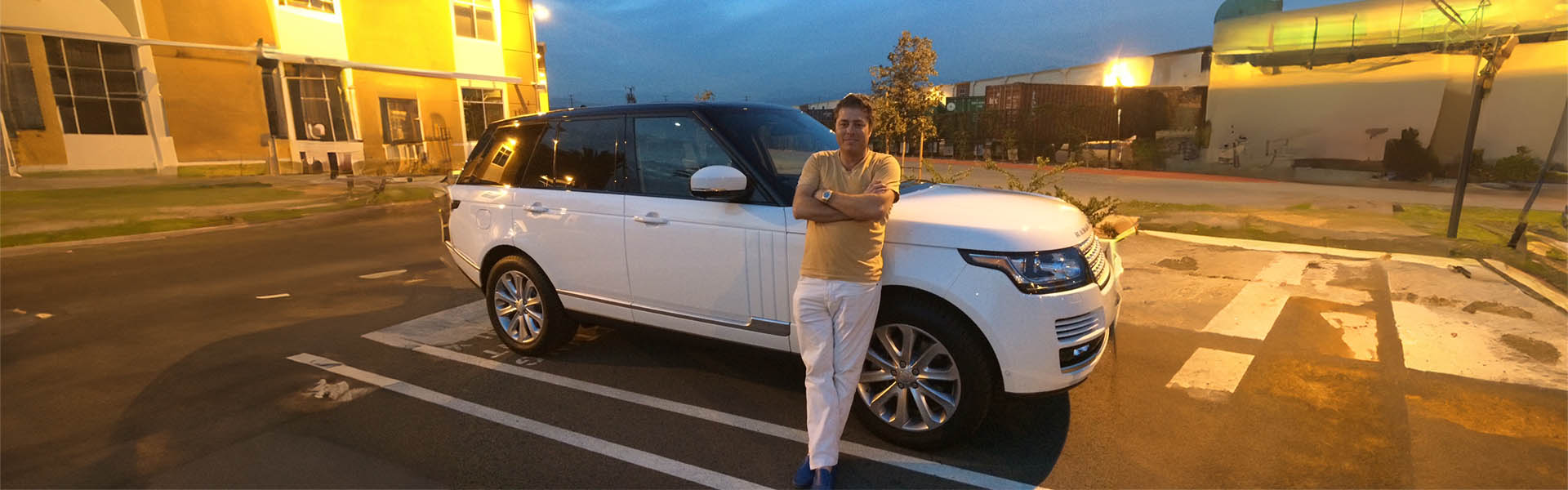 Tom Lawson leaning against a white Range Rover, representing the exceptional service and quality vehicles at Icon Servicing.